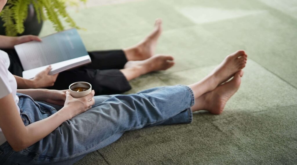 防音タイルカーペット静床プレミアオリーブグリーンが敷かれている部屋に人が座ってリラックスしている